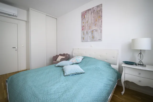 First bedroom with turquoise bedding and fitted storage