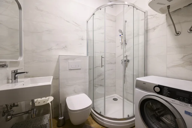 Washing machine beside the shower in the second bathroom