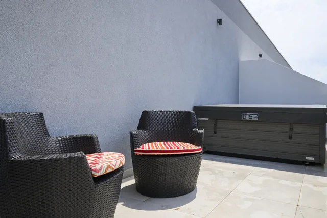 Terrace jacuzzi with its protective cover closed, beside outdoor seating