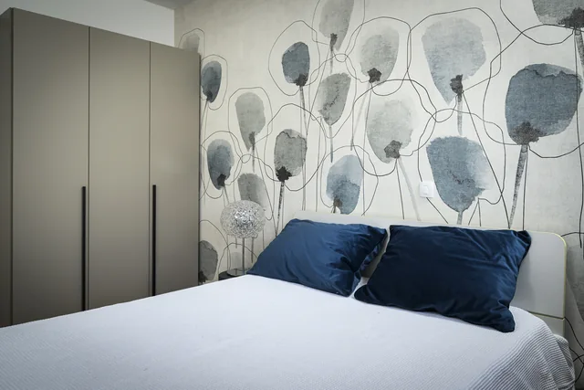 Second bedroom with blue cushions and botanical wallpaper