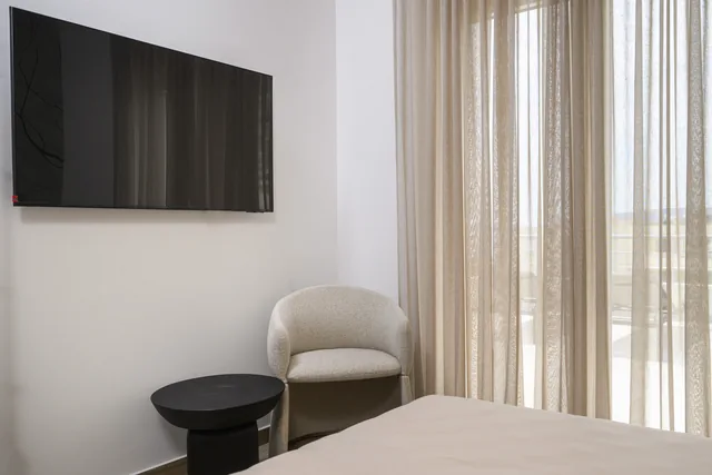 First bedroom armchair beside full-height curtains